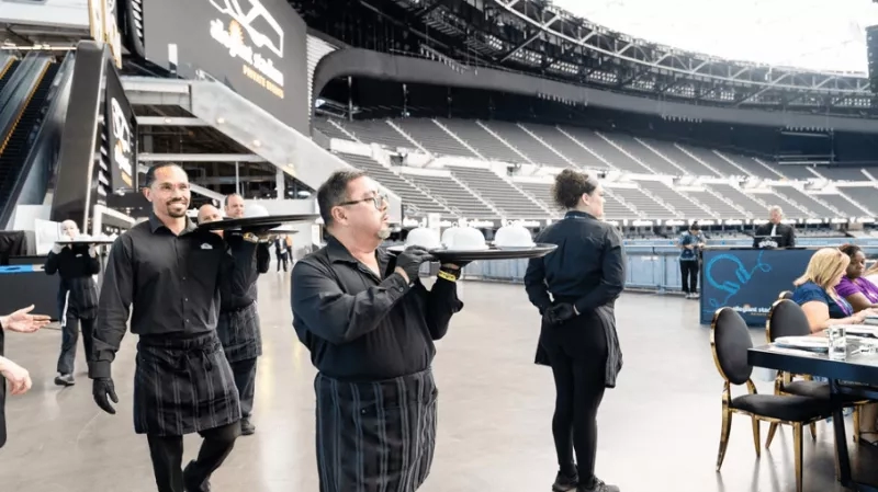 A group of people holding trays of food in a stadium at an event planning.