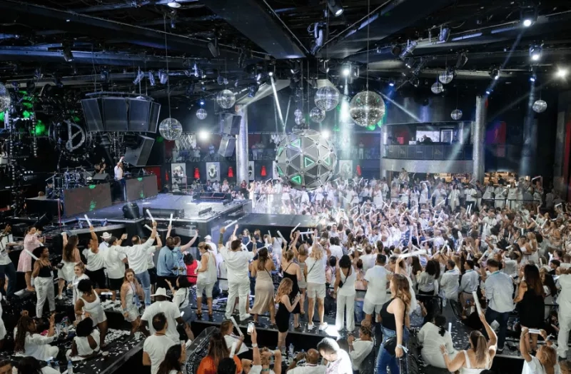 People are planning a business in a large room with disco balls and a crowd of people.