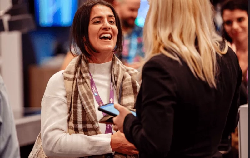 Two people are laughing while exchanging business cards at a Speed Networking event.