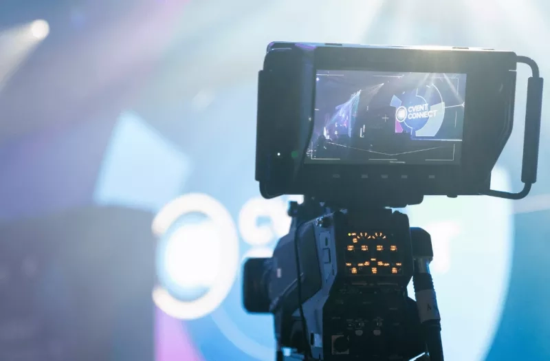 Video camera recording an event with the text "event connect" on a screen in the background.