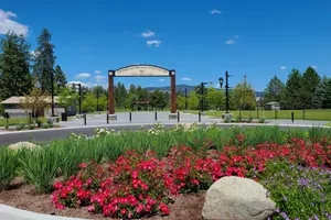 Flower bed, a sign, and a stone with trees in the background on a sunny day at CenterPlace.