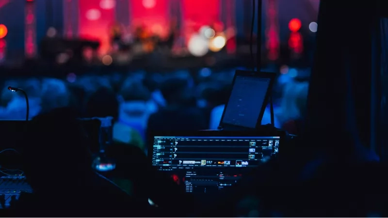 A group of people are enjoying the music at an event while watching the screen.