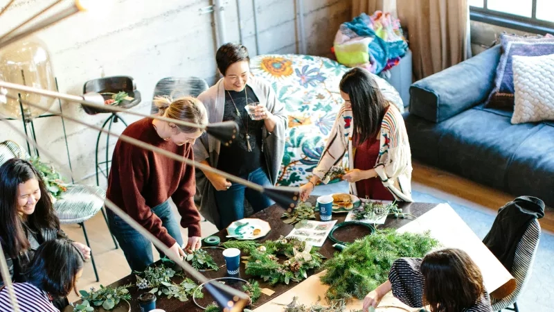 Team-building event with a group of women creating wreaths around a table.