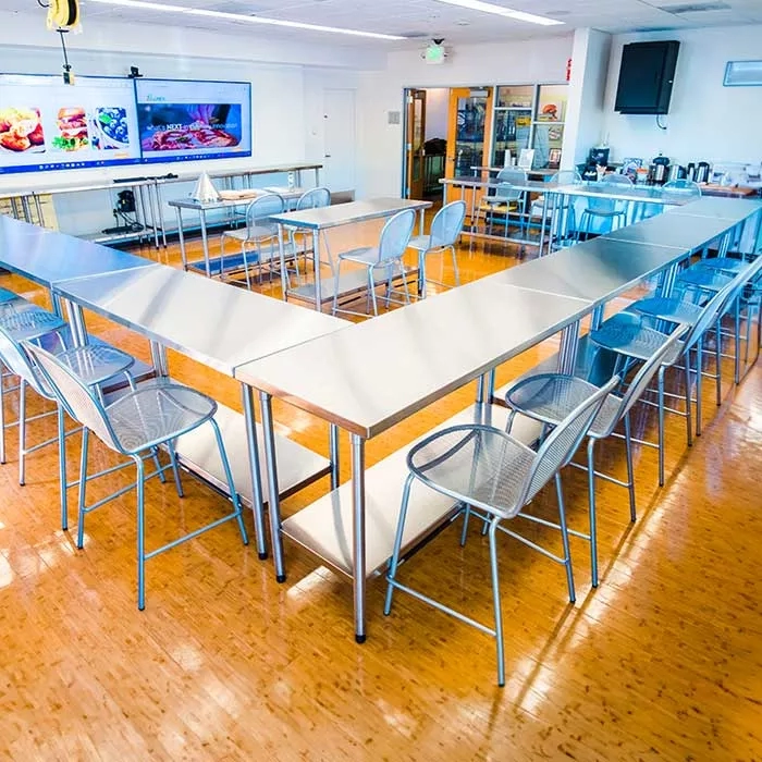 Meeting space at CuliNex with tables and chairs arranged in a U shape on a hardwood floor.