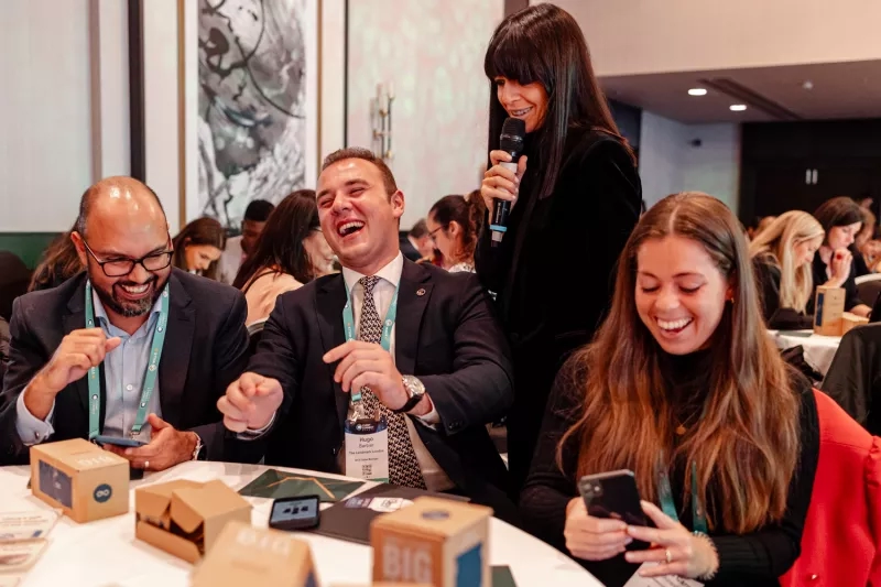 Hugo Barbier, standing with a microphone, laughs with other attendees at a BIG conference event.