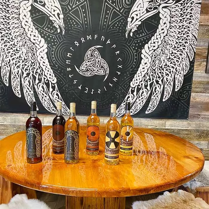 Six bottles of alcohol on a table with a backdrop of a large eagle in a room.