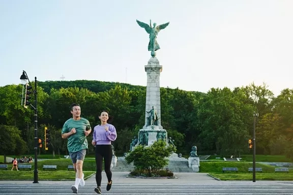 Couple jogging at Mount Royal with the monument of Sir George-Étienne Cartier in the background.
