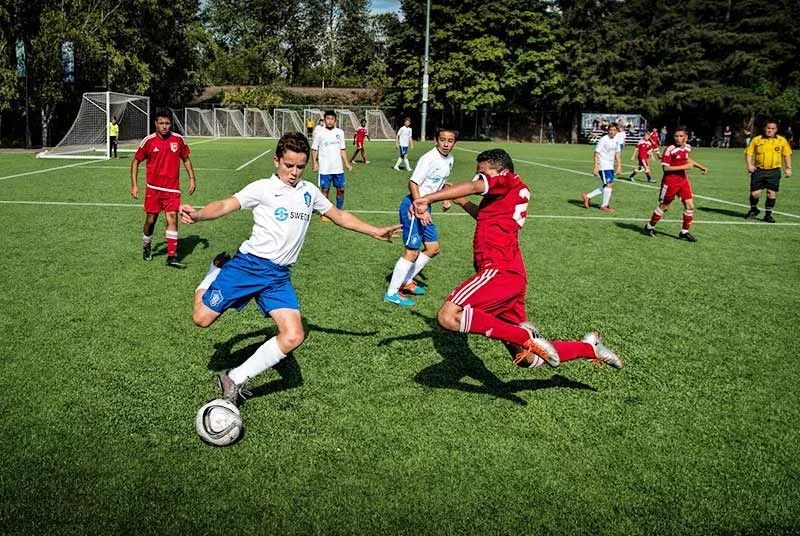 Soccer Starfire Sports Venue Tukwila, featuring players in action on a vibrant green field with lush trees in the background.
