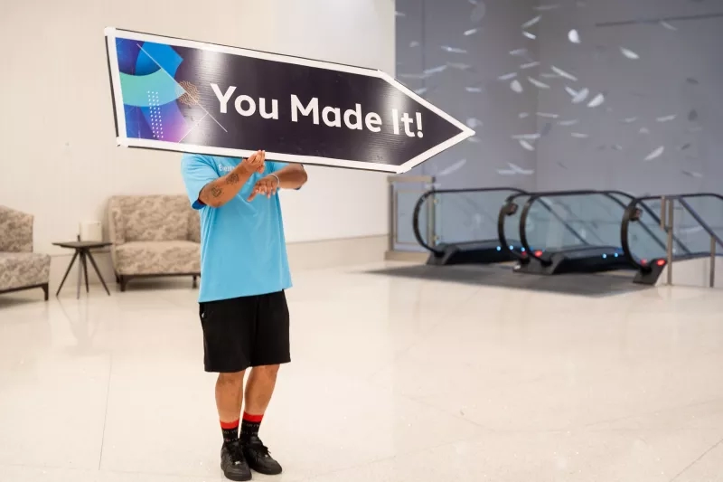 A man holding a sign that says You Made It in the lobby of Cvent headquarters.