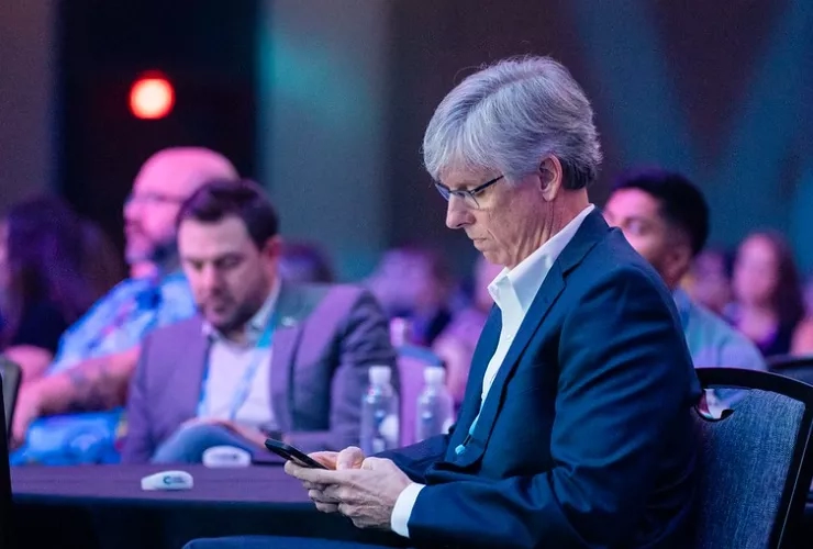 A person is using a cell phone while attending an event in a conference room.