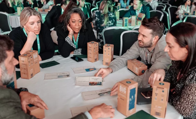 A group of people sit around a table with boxes that say "Big" on them.