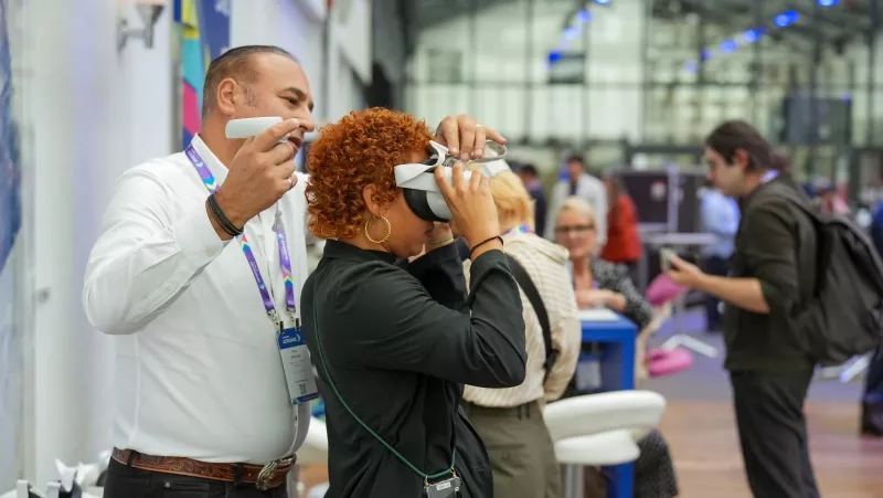 A woman trying on a VR headset at Cvent Accelerate, with people in the background.