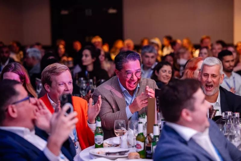 Attendees of the 2024 International Property Awards Dubai are celebrating and laughing at a dinner.