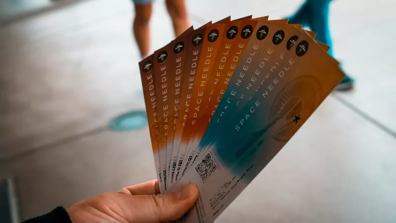 Person holding event tickets with the Space Needle on the front of each ticket.