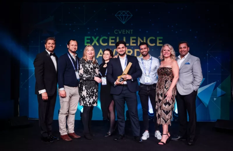 A group of people standing in front of a background that says CVENT EXCELLENCE AWARD.