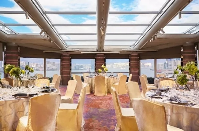 Elegantly decorated event venue with a glass roof and view of the city skyline.