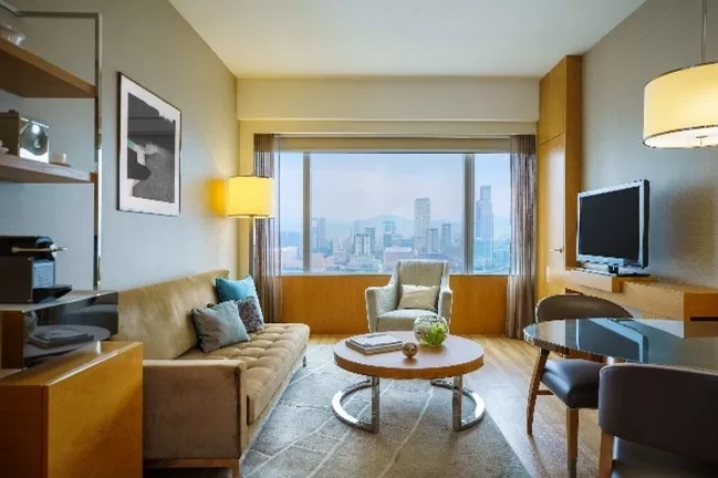 Interior of a suite with a living room and large windows at The Langham Hong Kong.