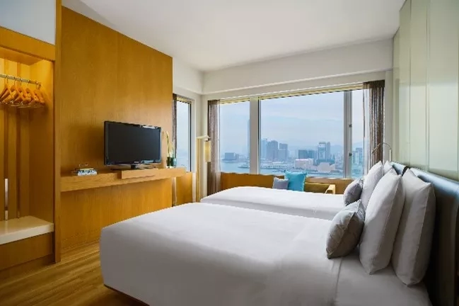 Hotel room with two beds, television, and large window showing city view at The Langham Hong Kong.