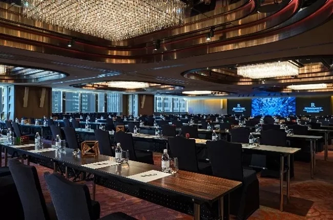 Conference room in Renaissance Beijing Wangfujing Hotel with rows of tables and chairs, and a large screen.