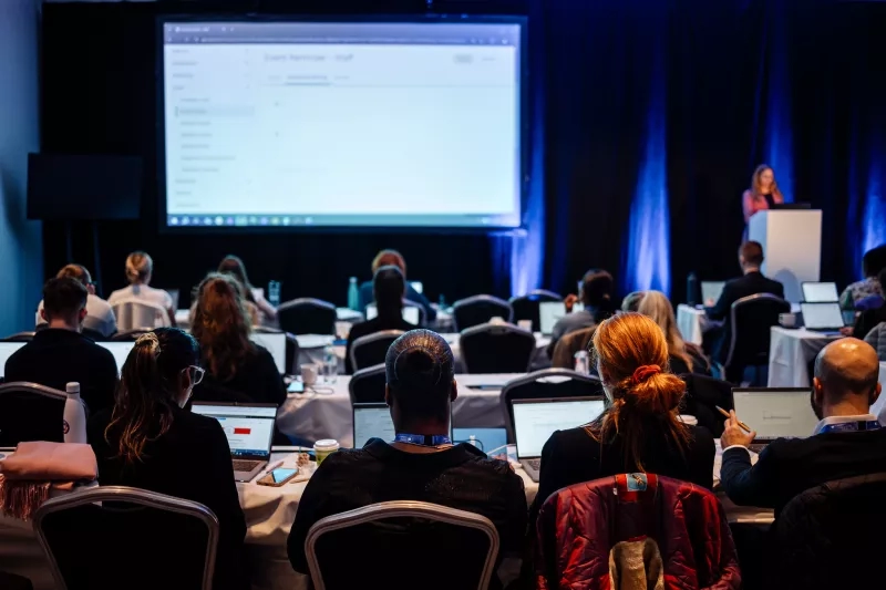Attendees sit at tables in front of a large screen during a Cvent CONNECT Europe 2024 session.