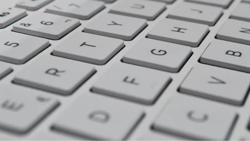 A close-up view of a white keyboard with keys "T", "G", "H", "B", and "V" visible.