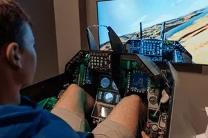 A young man sitting in a cockpit-style chair playing a flight simulator video game.