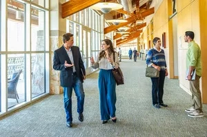 A group of people stand in a corridor with glass walls and a wooden ceiling at Palmer Events Center.