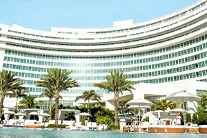 Fontainebleau Miami Beach exterior with pool and palm trees during the day.