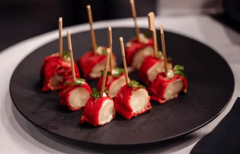 Close up of six mini mozzarella bites on a black plate on a white tablecloth