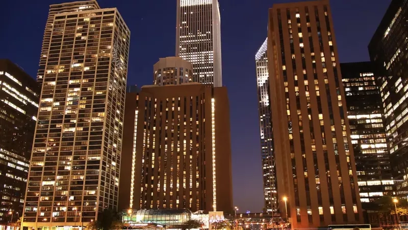 A cityscape at night with illuminated buildings, showcasing modern architecture and urban ambiance.