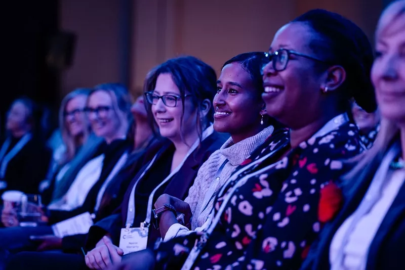 Three smiling women at an event, with event personalization.