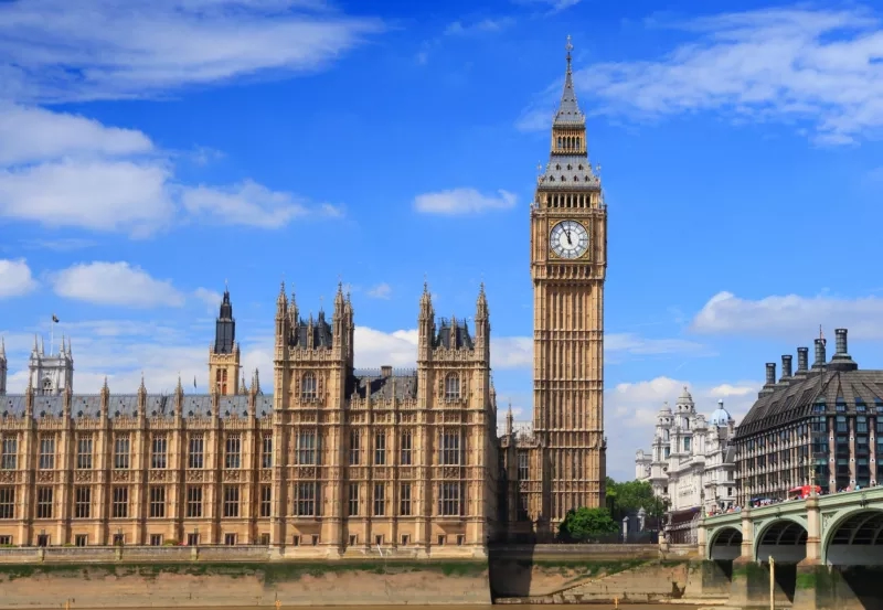 The Palace of Westminster features gothic architecture, a clock tower, and a bridge over a river.