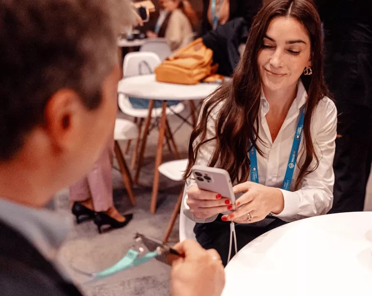 Woman smiling while looking at her phone while at an event with a chatbot.