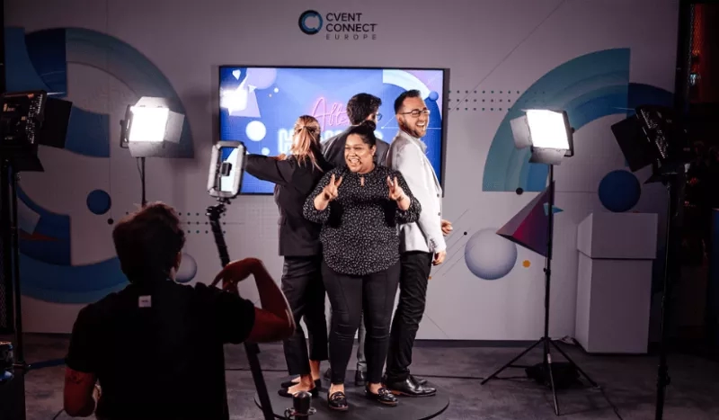 Four people smiling in front of a screen with event photography equipment in front of them.