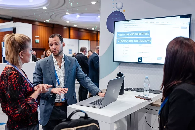 People at an event looking at a laptop that has a screen saying "Automation Integrations" on it.