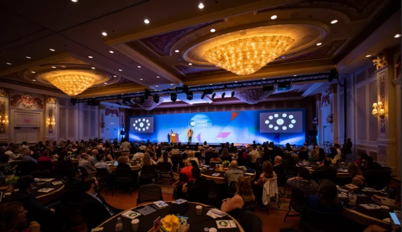 a person standing on stage and hall full of people