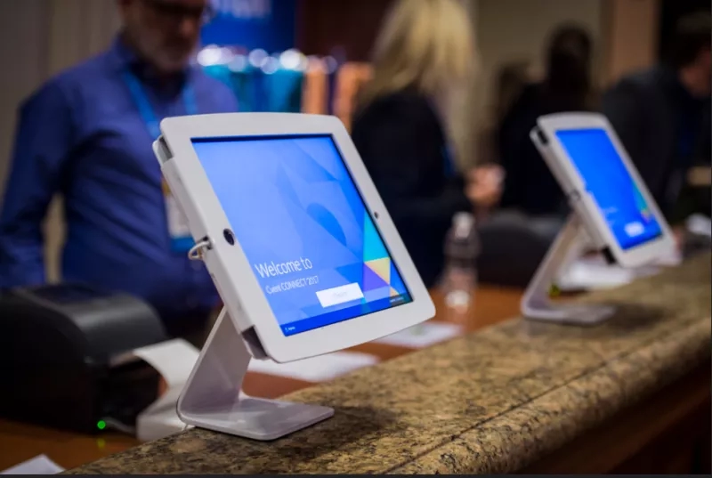 Two tablets with a welcome screen on them sit on a desk at a conference event.