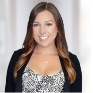 Female person with brown hair wearing a black jacket and white blouse smiling at the camera.