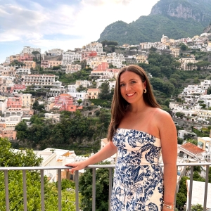A woman in a blue dress standing on the balcony of a villa in Positano.