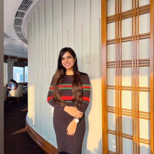 A woman with long hair standing next to a wall inside a hotel.