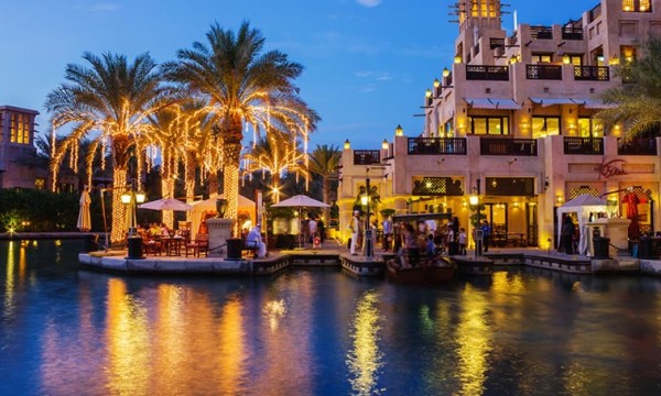 Hotel exterior at night with string lights and water transport in Dubai Marina.