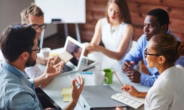 A group of business people are having a meeting and discussing something while sitting around a table.