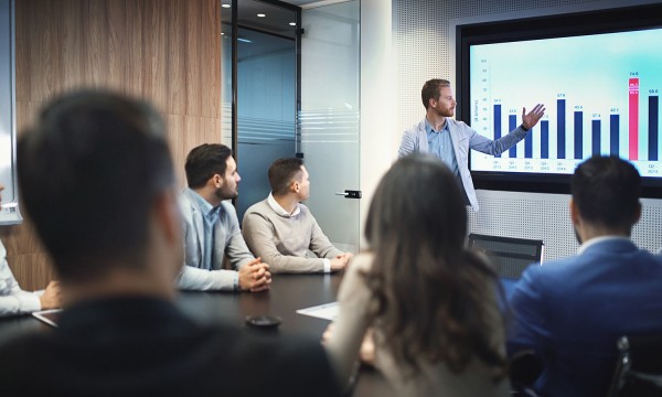 man pointing at powerpoint during sales presentation