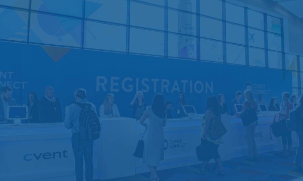 Several people are standing in front of the registration desk with a blue banner behind them.