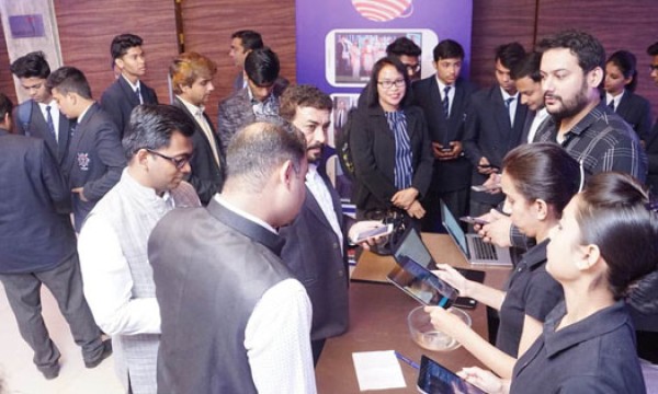 Several people are gathered around a table with laptops and tablets, possibly in an event.
