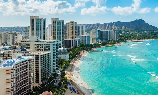 A cityscape of hotels and resorts on a beach with mountains in the background.