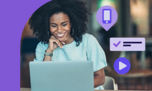 Woman with afro hair smiling while using a laptop in an office with icons around her.
