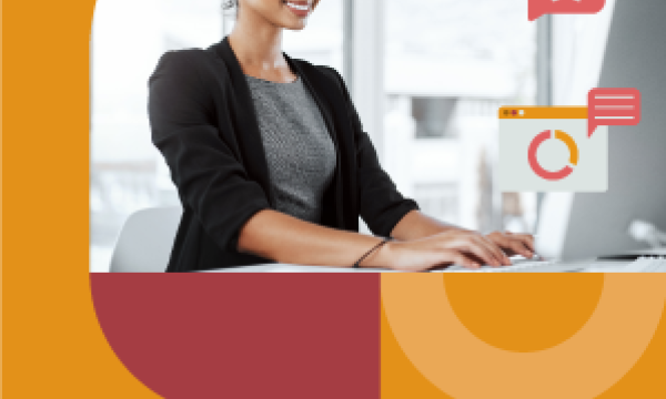 An image of a smiling woman working on her laptop in an office with a colorful background.