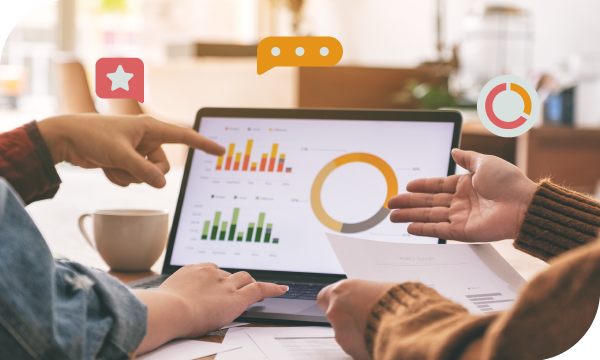 Two people discussing graphs on a laptop with social media icons above.