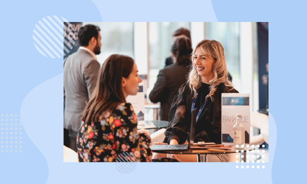 Two women talking at an event with a Bankside brochure on the table.